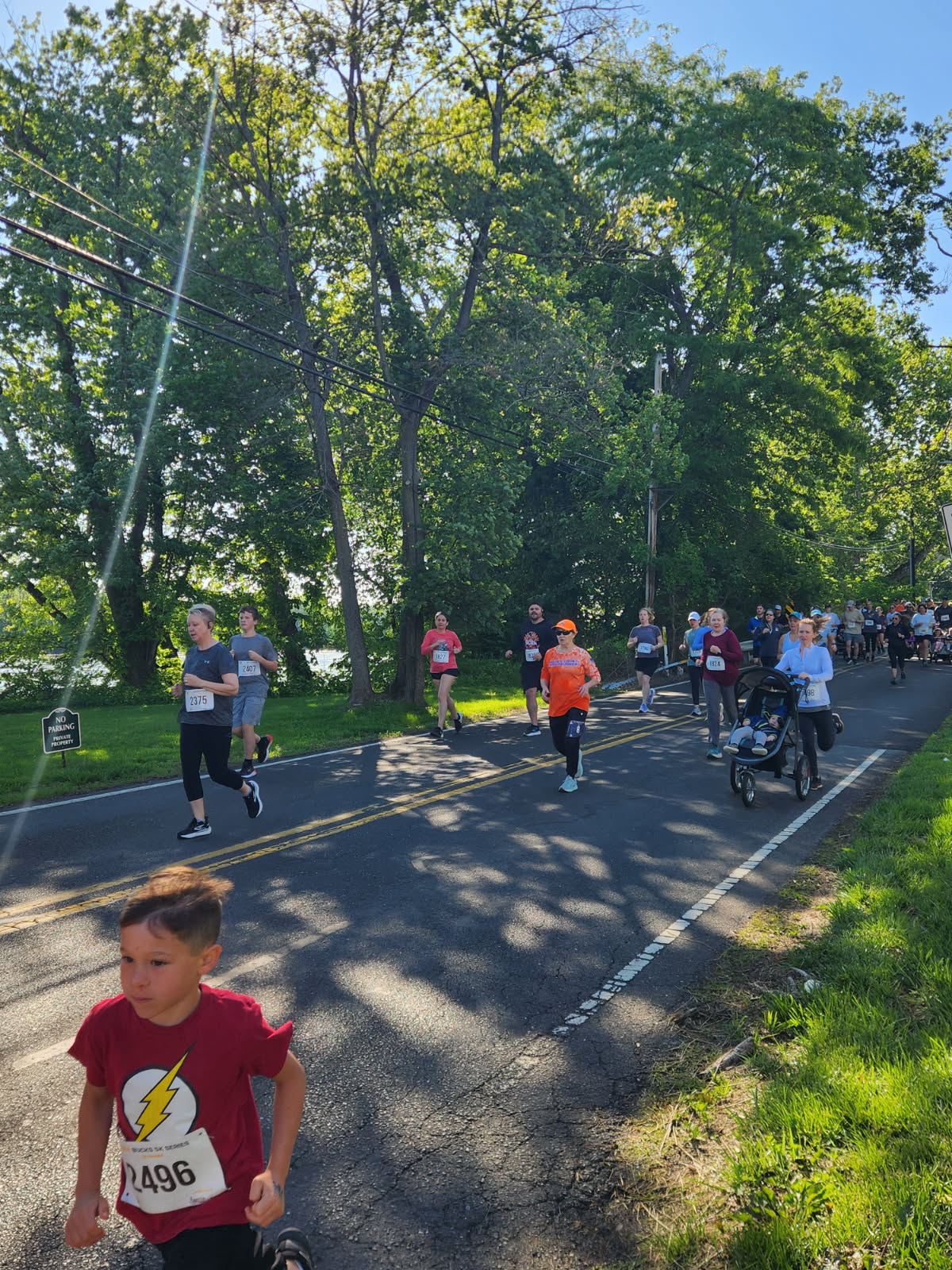 A young runner in a red shirt sprinting ahead of the pack at the Yardley 5K